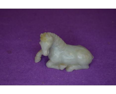 A Chinese Nephrite or Jade figure of a resting horse in a pale green tail being damaged otherwise good appro 10cm long