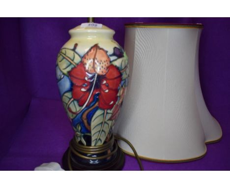 A Moorcroft lamp base having lily and vine type design on cream ground.