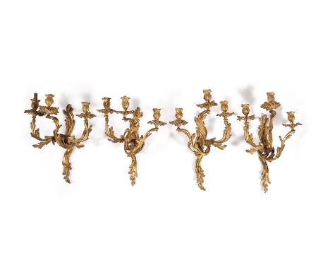 A SET OF FOUR LOUIS XV GILT METAL THREE LIGHT WALL APPLIQUESMID 18TH CENTURYEach in Rococo taste and with a floral cast sconc