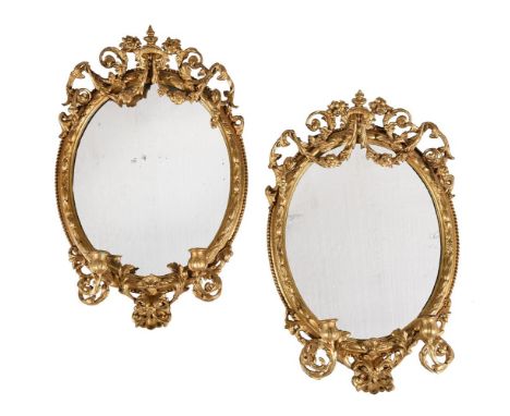 A PAIR OF VICTORIAN GILTWOOD AND COMPOSITION OVAL WALL MIRRORS SECOND HALF 19TH CENTURY Both with twin scrolling candle arms 