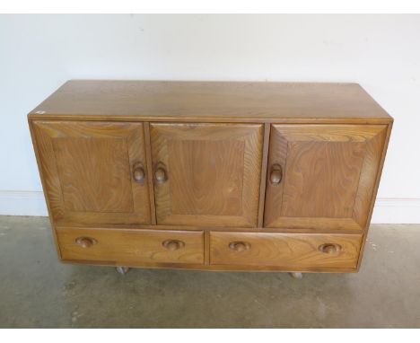 An Ercol blonde elm and beech sideboard with three cupboard doors over three drawers, missing its internal shelf, 130cm W x 4