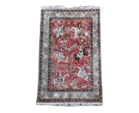 An early 20th century Tabriz pictorial red ground rug, woven with hunters on horseback,the border decorated with animals amon
