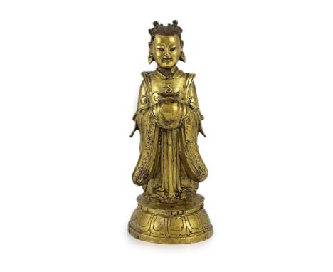 A Chinese Ming gilt bronze figure of an immortal, 16th/17th century,the figure standing and holding a jewel, on a lotus base,