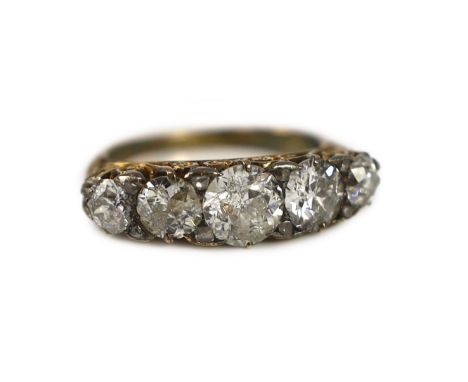 An early 20th century 18ct gold and graduated five stone diamond set half hoop ring,with carved scroll setting and diamond ch