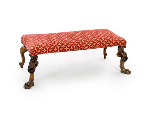 A Victorian long stool,with padded top and ornately carved oak cabriole legs, with flowers and lions paw feet to one side and