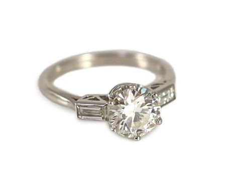 A platinum and single stone diamond ring, with baguette cut diamond set shoulders,the central stone weighing approximately 1.