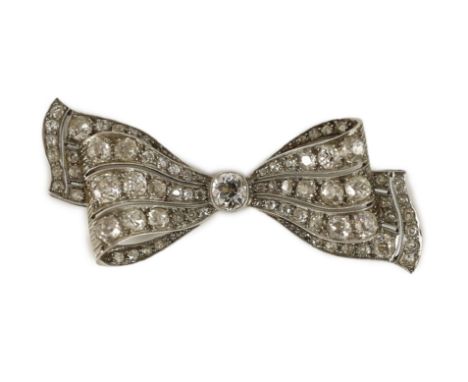 An early to mid 20th century white gold and graduated diamond cluster millegrain set ribbon bow brooch,the central stone weig