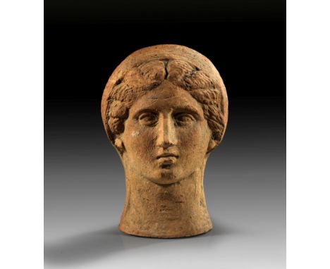 Weiblicher Votivkopf. Magna Graecia, 3. Jh. v. Chr. H 23,1cm. Rötlicher Ton. Matrizengeformt. Kopf einer Frau mit Melonenfris