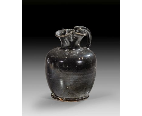 Apulische Oinochoe. 2. Hälfte 4. v. Chr. H 15,8cm, ø Körper 11,9cm, ø Ringfuß 8,7cm. Kanne der Form 2 mit Glanzton. Bis auf w