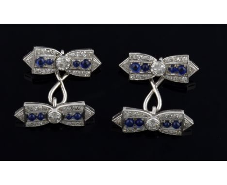 A pair of double diamond and sapphire cufflinks, each link in a bow motif with an old cut diamond to the centre. cabochon cut