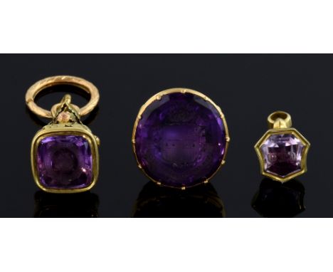  Three antique fobs, each set with amethyst, intaglio cut, two heraldic, one with initials, set in unmarked gold   22.4 grams