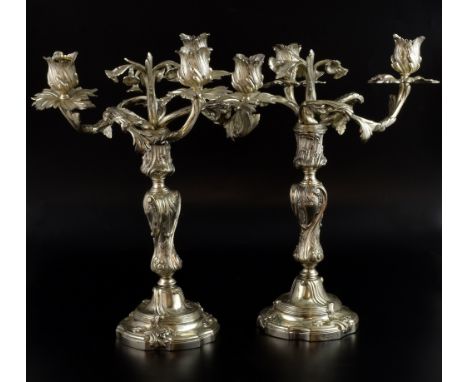 Pair of silver plated three light candelabra with floral and scrolling decoration on shaped bases, 35cm high, 