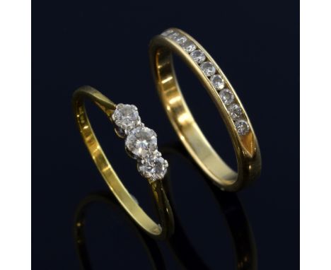 Two diamond set rings, a three stone diamond ring, in 18 ct gold, ring size M  and a band ring channel set with diamonds,14 c