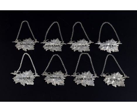 Set of eight modern silver decanter labels in the form of vine leaves, comprising, Claret, Vodka, Whisky, Port, Sherry, Rum, 