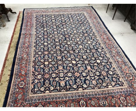 A Persian carpet, the central panel set with repeating floral decoration, on a blue ground, within a stepped pale blue and pa