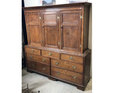 A 19th Century oak housekeeper's cupboard, the canted cornice above three twin panelled doors enclosing shelving, on a base o