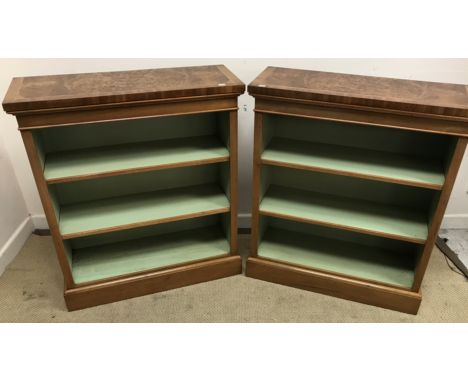 A pair of walnut open bookcases in the Georgian manner, the figured feather-banded and cross-banded tops over an open painted