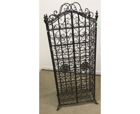 A modern patinated iron scrollwork wine cage in the 19th Century manner, the two doors opening to reveal a 66 bottle rack, 68