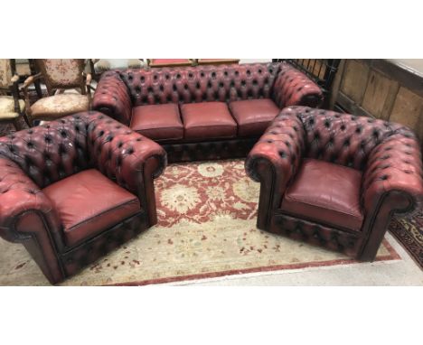 A modern red leather buttoned Chesterfield scroll arm three seat sofa, 180 cm wide, together with a pair of matching armchair