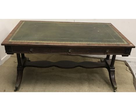 A reproduction mahogany library table in the Regency manner, the top with tooled and gilded leather insert, over three frieze