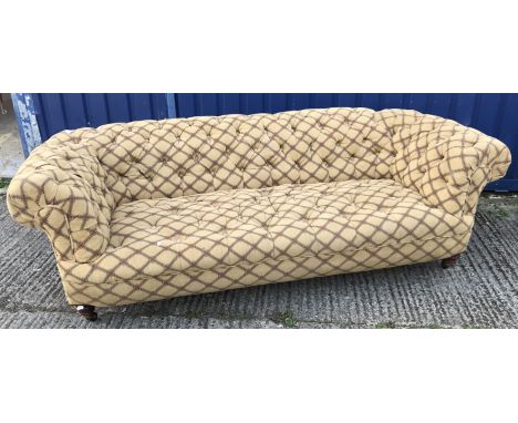 A late Victorian buttoned upholstered scroll arm Chesterfield type sofa on turned mahogany front legs to castors, 220 cm wide
