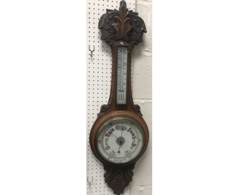 A late Victorian carved oak cased banjo barometer thermometer with mercury thermometer over an aneroid barometer, 88 cm high
