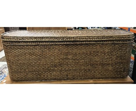 A modern basket work trunk of long slim design, the top opening to reveal a lift-out tray, 150 cm wide x 42 cm deep x 55 cm h