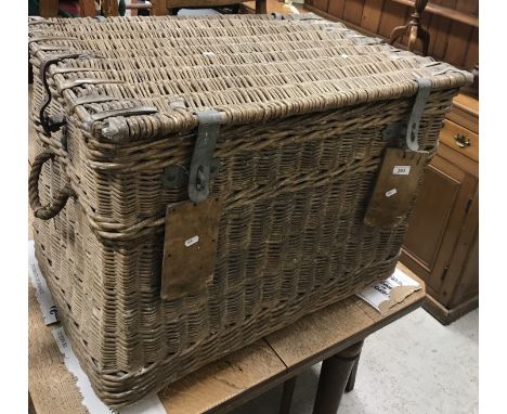 A vintage wicker laundry basket with hide reinforcements to the top and galvanised hasp and staple locks, flanked by ropework