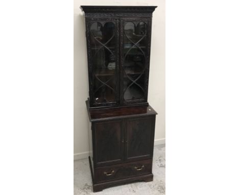 A circa 1900 carved mahogany bookcase cabinet, the upper section with two glazed doors enclosing adjustable shelving over two