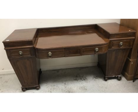 An early 19th Century mahogany breakfront sideboard, the centre bowed section sunken, with a small drawer, flanked by two dee