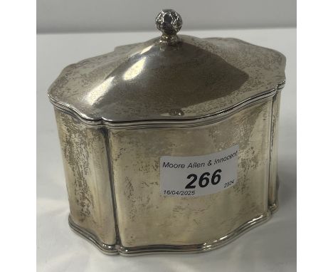 A George V silver tea caddy of shaped form, the hinged lid with stylised flower head finial (by William Hutton & Sons Ltd, Bi