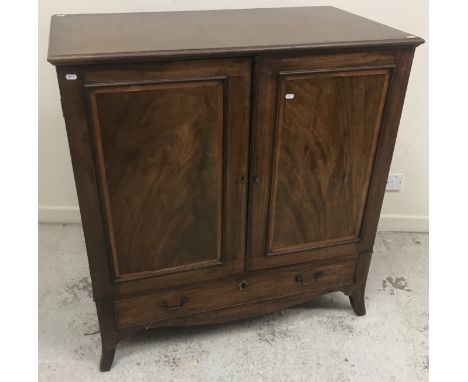 An early 19th Century mahogany linen press, the plain top with moulded edge over two panelled cupboard doors enclosing shelvi