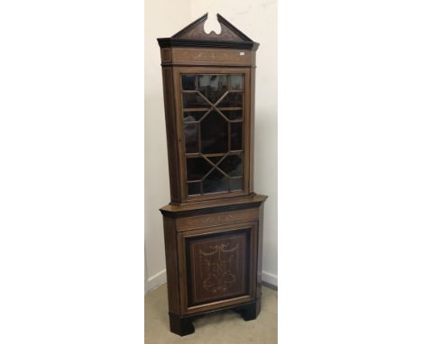 An Edwardian mahogany and inlaid Sheraton Revival corner cabinet, the broken arch pediment over a single glazed door enclosin