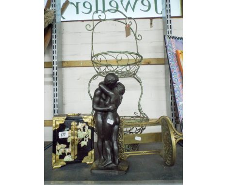A two tier metal flower basket, a naked man and woman embracing, a small cabinet with oriental decoration and a small glass h
