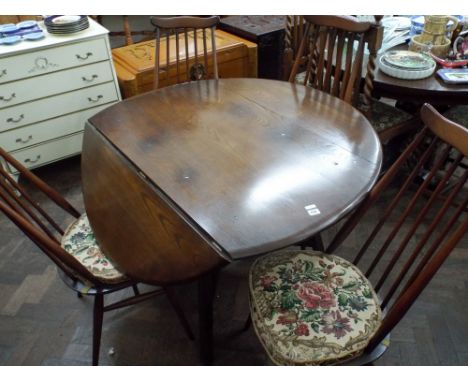 An Ercol circular oak drop leaf dining table with four matching stick back chairs with seat pads 