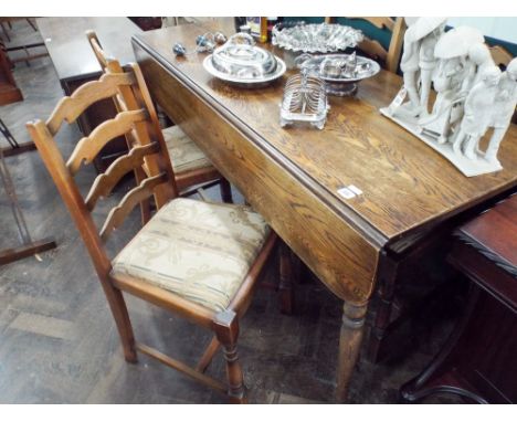 A 5' long oak drop leaf dining table on turned legs together with 4 ladder back style chairs 