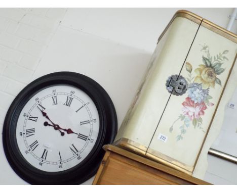 A large circular wall clock and a floral painted dome top trunk