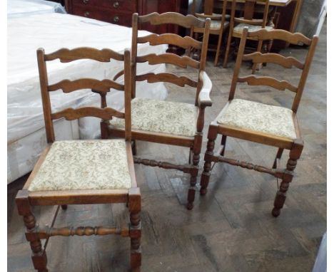 A pair of oak ladder back dining room chairs with one matching carver, the seats are upholstered in the same material as the 