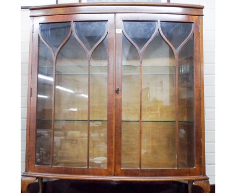 A bow fronted two shelf china cabinet on cabriole legs