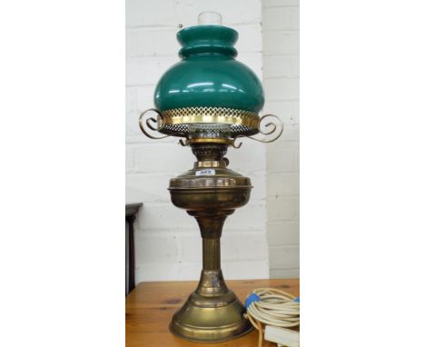 A brass oil lamp converted to electricity with a green shade
