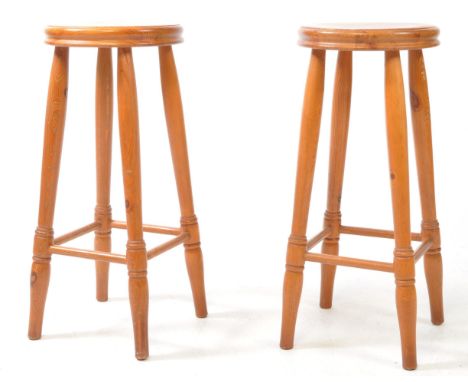 A pair of vintage 20th century pine bar / pub kitchen stools. Circular seat with four turned leg supports united by perimeter