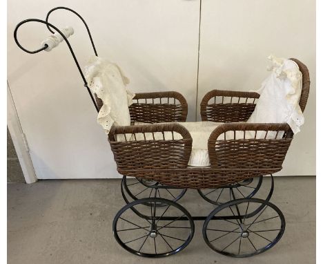 A reproduction double ended black metal and wicker body dolls pram with floral ceramic handle. Complete with broderie anglais