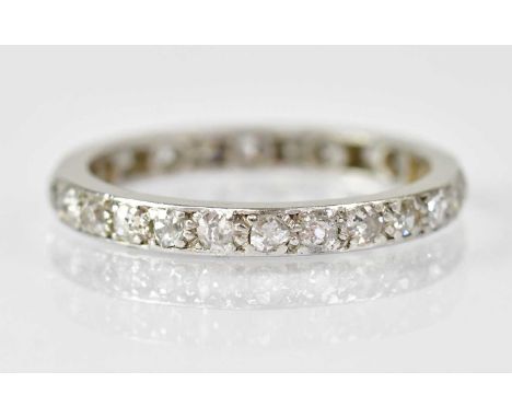 A white metal eternity ring set with approximately twenty-seven small diamonds, size M, unmarked, approx. 2.8g.Condition Repo