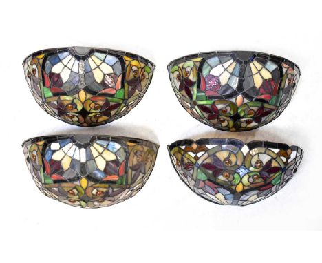 A set of four Tiffany-style leaded glass wall lights with scrolls, floral motifs and orange roundel decoration, height of eac