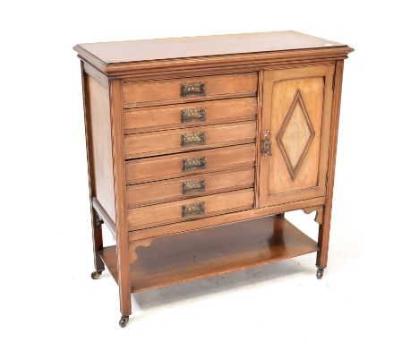 An Edwardian mahogany music cabinet comprising six drawers with fall fronts and a cupboard above an open shelf, on fluted leg
