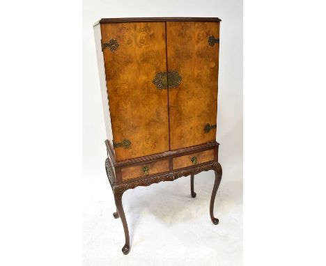 A mid-20th century walnut drinks cabinet with a pair of cupboard doors and fitted interior, on a separate base with a pair of