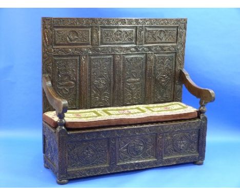 A 17thC profusely carved oak Box Settle, the multiple panelled back carved with central date '1632', 'Green Man', bird, flora