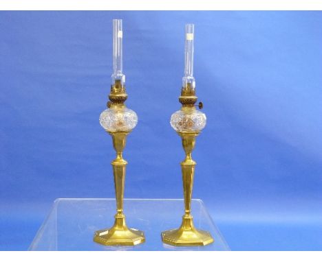 A pair of early 19thC brass candlestick Oil Lamps, each with a small cut glass spherical reservoir, 22in (56cm) high.