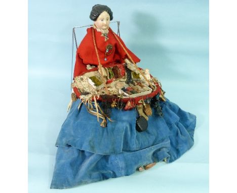 A Victorian Pedlar Doll, c.1850, with porcelain head and hair, blue velvet full skirt, the full tray of wares and trinkets in