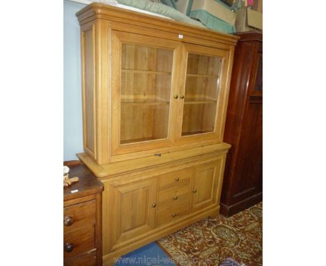 A contemporary light Oak living room Display Cabinet over a base with a flight of three central drawers flanked by cupboards,